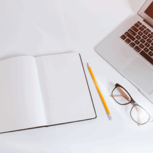 Bureau de travail avec carnet, crayon et ordinateur pour traduction, rédaction et révision de contenus professionnels.