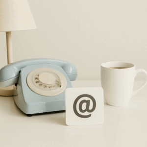 espace de travail épuré avec téléphone, enveloppe et symbole @ pour illustrer le contact en traduction et rédaction