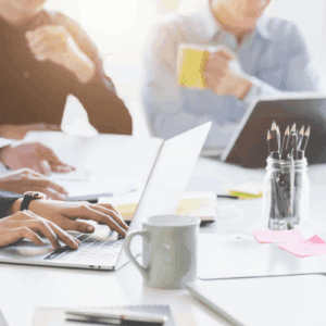 session de travail en équipe avec ordinateurs portables et stylos, illustrant une formation professionnelle sur mesure en anglais. formation et coaching