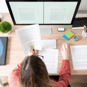 Professionnelle relisant des documents techniques sur écran et papier dans le cadre d'une traduction, rédaction ou révision de contenus en anglais